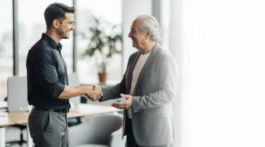 Jeune professionnel échangeant avec un mentor expérimenté dans un cadre de travail lumineux, symbolisant la construction d'un réseau de conseillers