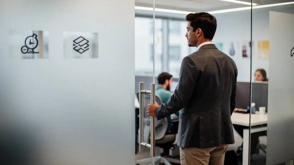 Jeune professionnel confiant observant un openspace lumineux le premier jour dans une nouvelle entreprise
