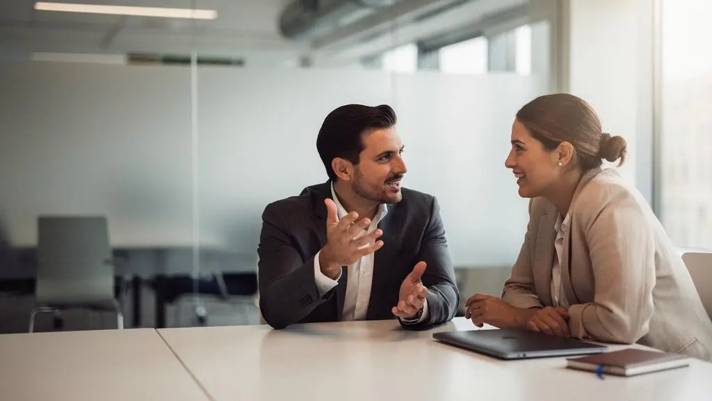 Deux professionnels engages dans un echange authentique et chaleureux lors d'un entretien, illustrant la valeur des competences humaines